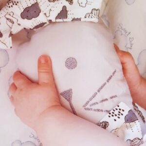 mão de bebê segurando naninha orelhuda