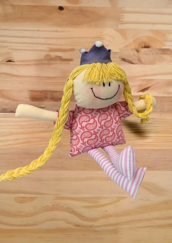 boneca de pano rapunzel com vestido rosa estampado em lilás, coroa lilás e tranças louras longas